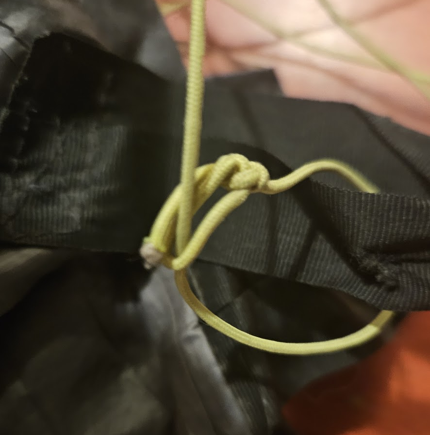 Guyline attached to a tarp tie-out via girth hitch -- cord passes through the ring and back through the bowline, no knot tied to the hardware