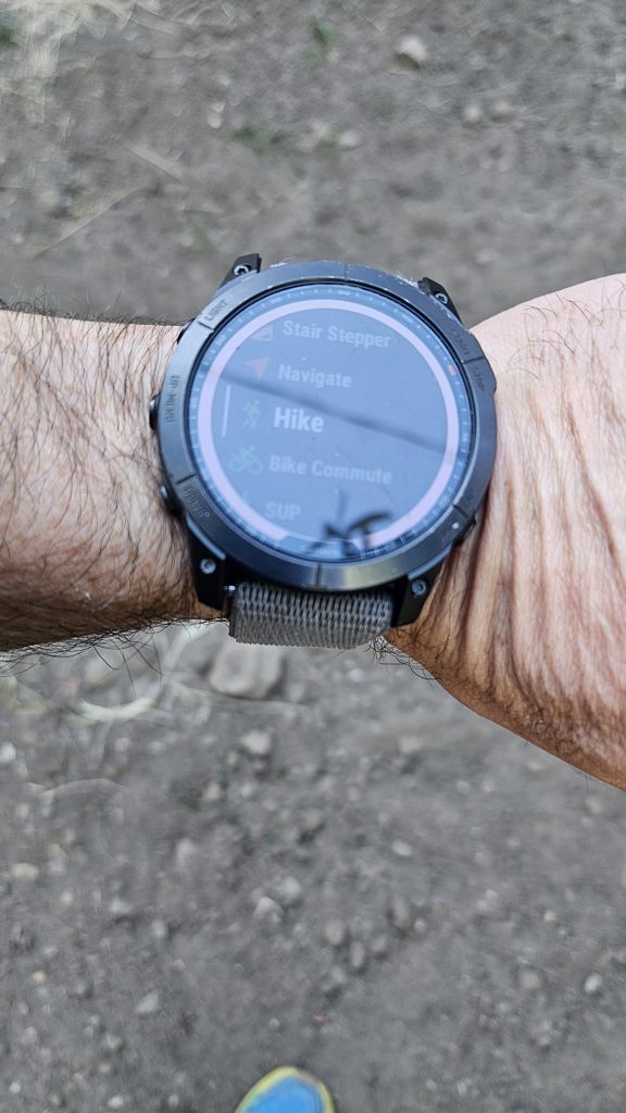Garmin Fenix 7X on a wrist showing the activity list with Hike selected and Navigate just above it